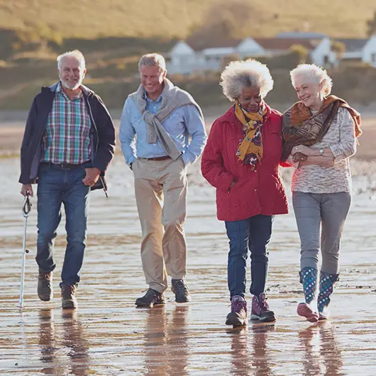 Couples walking on beach on a cool day with an improved quality of life.
